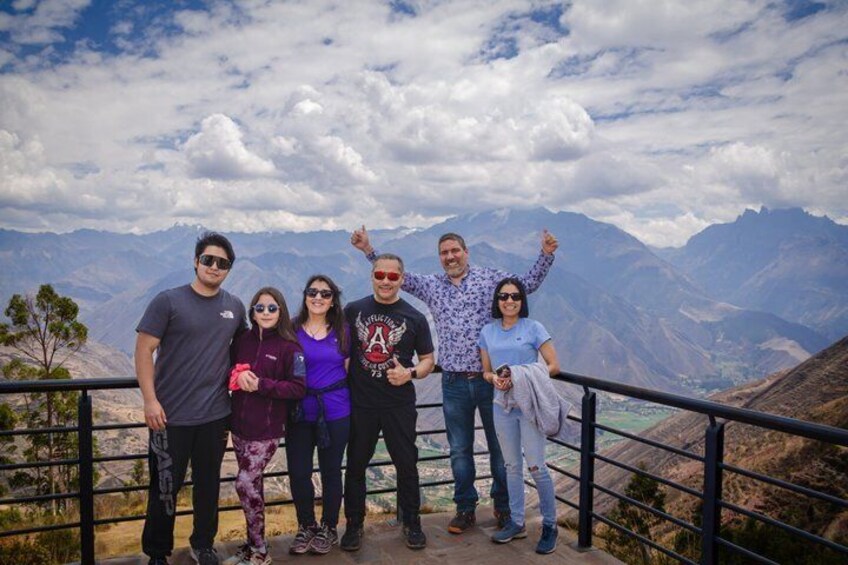 A group of people standing on a viewing platform with a mountainous landscape in the background. 2
