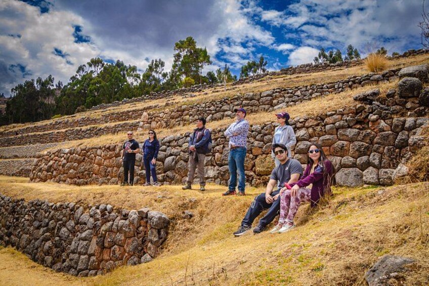A group of people standing and sitting on a stone slope with a clear sky above. 3