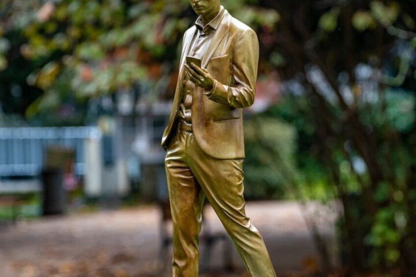 A golden statue of a man in a suit walking. 3