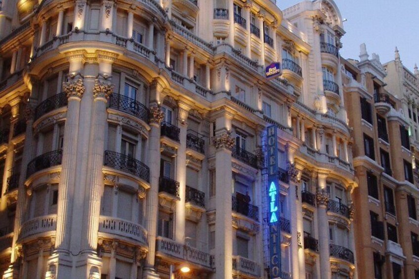 A historic building with ornate architecture, including columns and balconies, and a prominent illuminated sign. 4