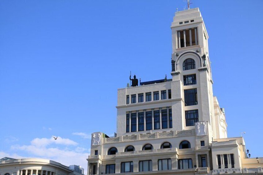 A white building with a clock tower, arched windows, and a balcony. 2