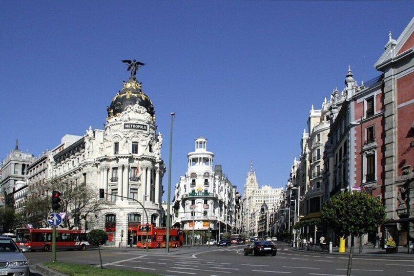 A city street with a prominent building featuring a golden dome and a statue on top, surrounded by classic architecture. 5