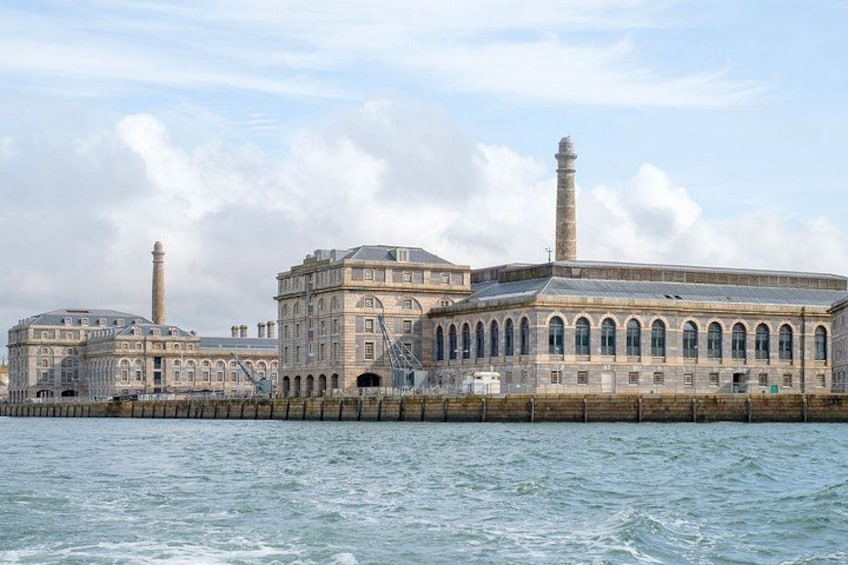 A large, historic building with a prominent tower and arched windows, situated by a body of water. 1