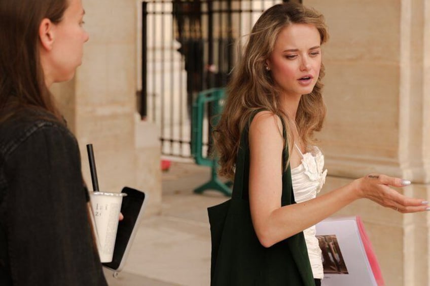 A woman in a green dress holding a folder and a drink with a straw. 5