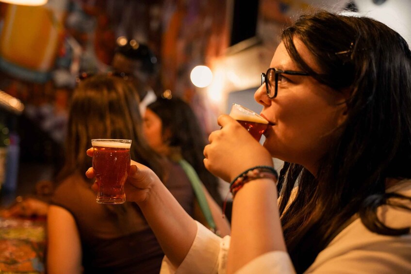 A person holding a glass of beer in a dimly lit indoor setting. 4