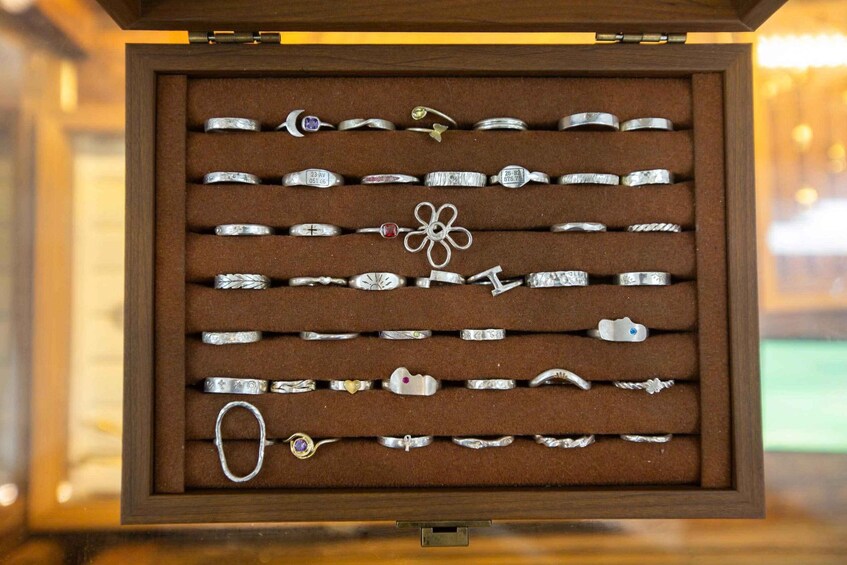 A jewelry box with multiple silver rings and a few bracelets. 3