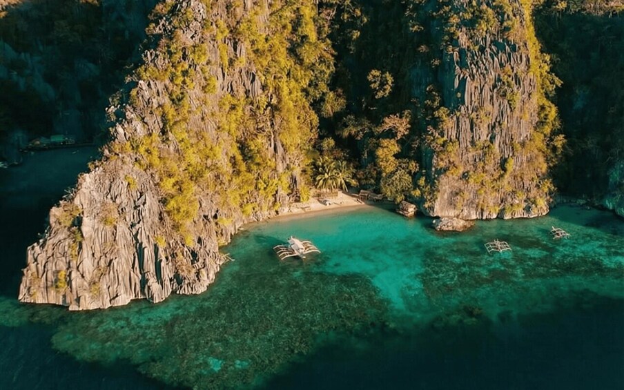 A coastal landscape with rocky cliffs, clear turquoise waters, and a small boat anchored near the shore. 1