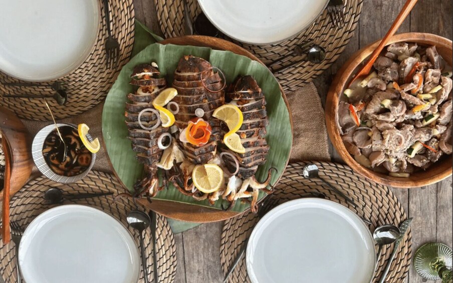 A variety of seafood dishes on a woven mat, including fish and shellfish, garnished with lemon slices. 4