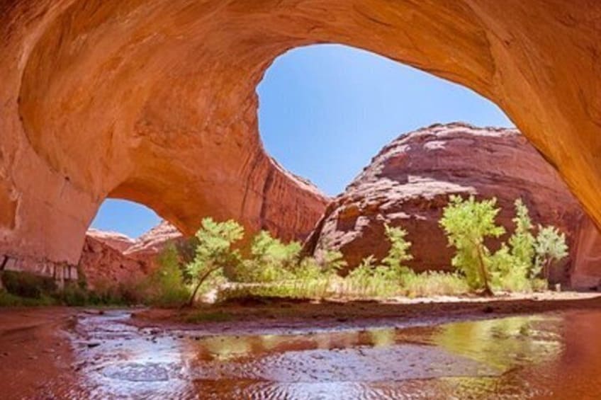 A natural rock arch formation with a river flowing through it. 4
