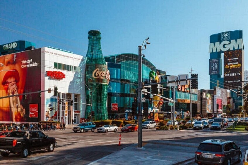 Una concurrida calle urbana con un gran anuncio de Coca-Cola, un letrero de casino y un imponente edificio de cristal. 2