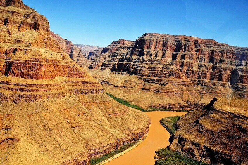 Un cañón con formaciones rocosas estratificadas y un río. 5