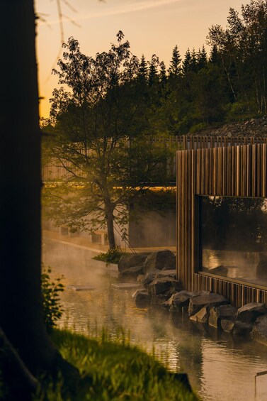 A serene outdoor setting with a wooden structure, a calm body of water, and surrounding greenery. 2