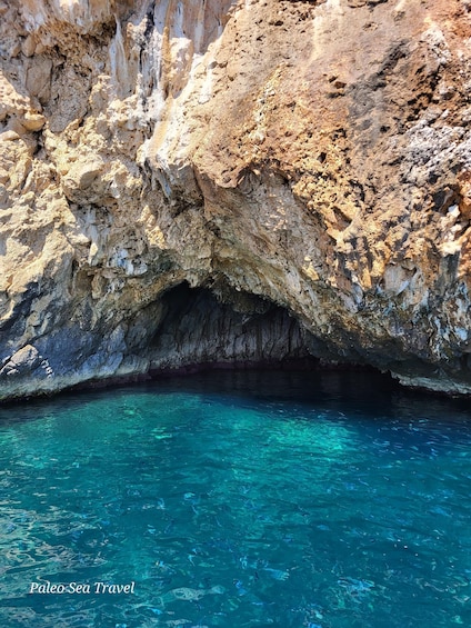 A rocky cave entrance with clear blue water. 2