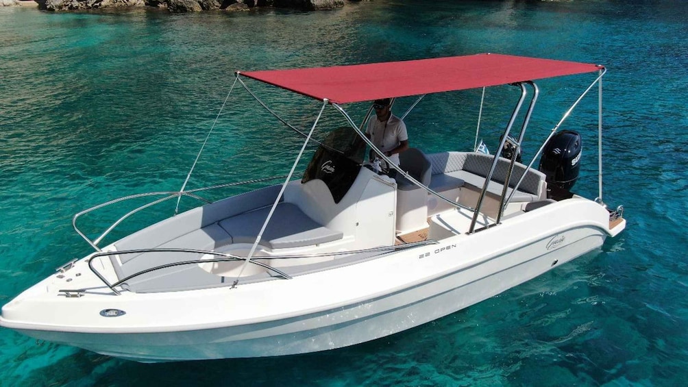 A small white motorboat with a red canopy, anchored in clear turquoise water. 3
