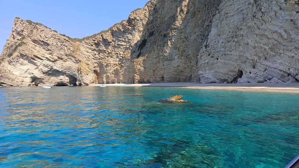 A clear blue sea with a rocky cliff and a boat. 4