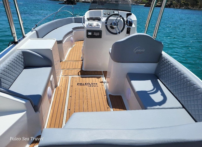 A boat's interior with a wooden deck, cushioned seating, and a steering wheel. 5