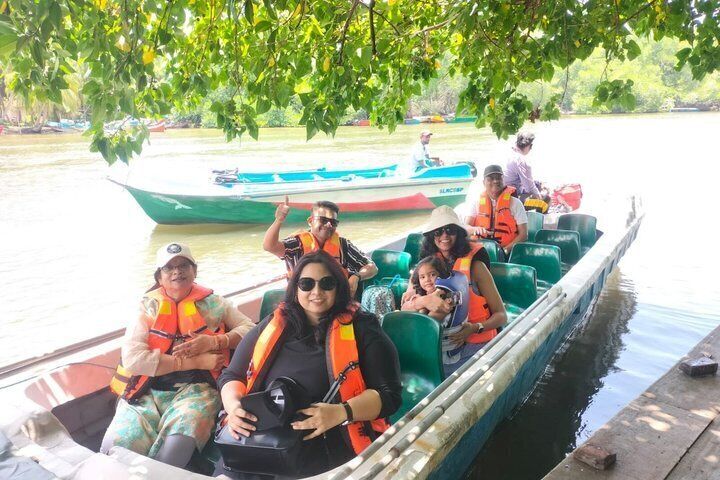 A group of people on a boat, wearing life jackets, with a river and another boat in the background. 5