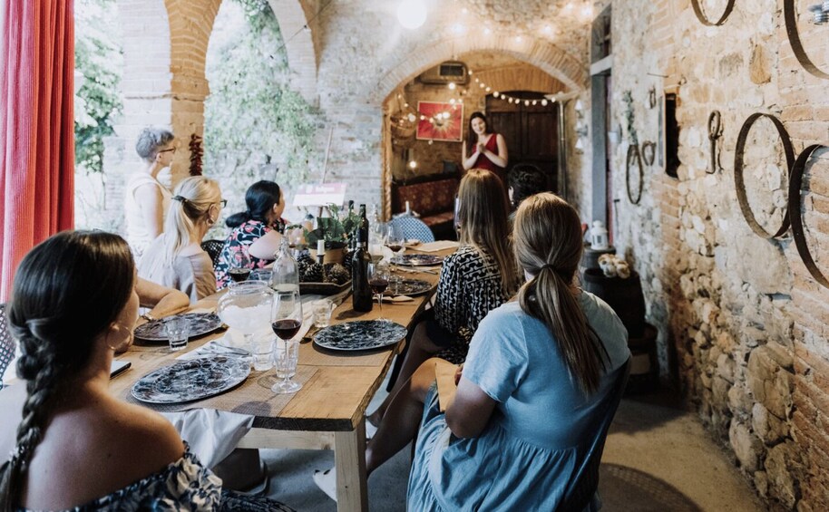 Un gruppo di persone cena in un'accogliente trattoria con pareti in pietra, luci appese e biciclette d'epoca alle pareti. 3