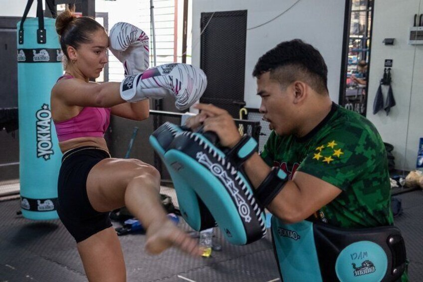 A person practicing kickboxing with a punching bag in a gym. 4
