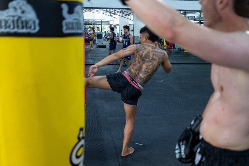 A person practicing martial arts, wearing black shorts and a black top, with tattoos on their back. 2