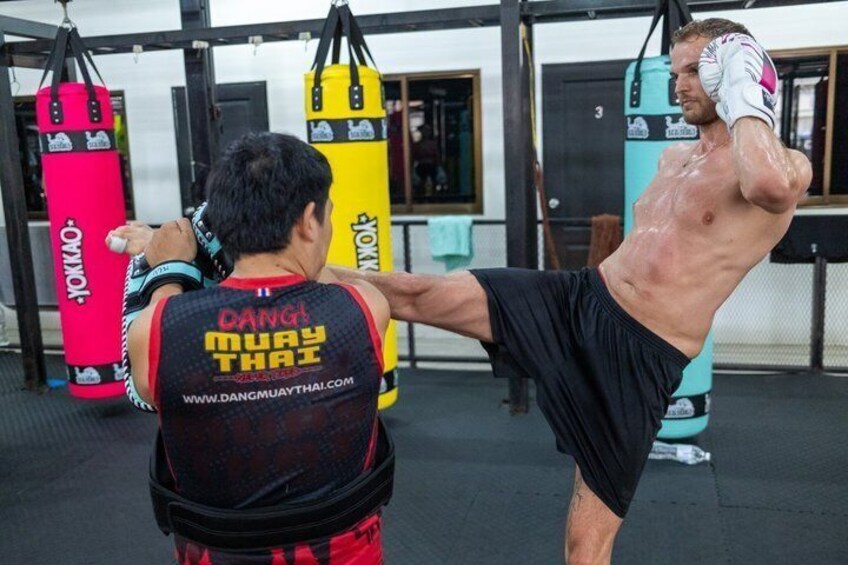 A person practicing martial arts in a gym with punching bags. 5