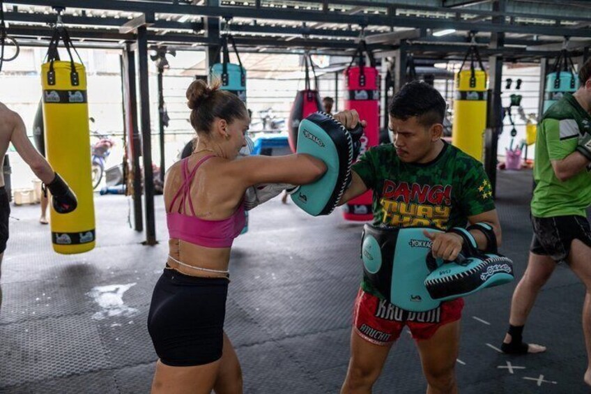 A person practicing boxing with a focus mitts in a gym. 1