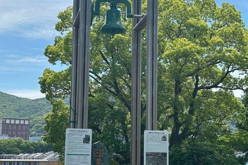 A tall, green bell structure with informational signs in front. 2