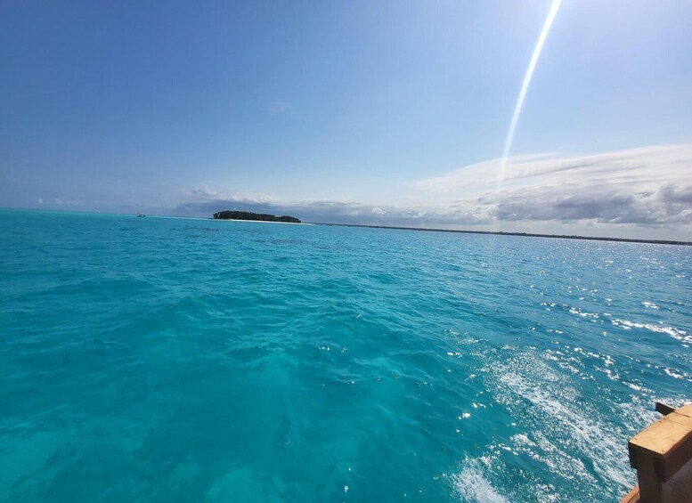 A clear blue sea with a small island in the distance and a sun shining from the right. 3