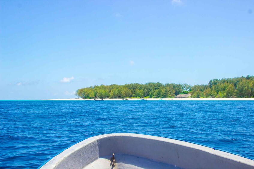 A boat on a calm sea with a sandy beach and a forested island in the background. 4