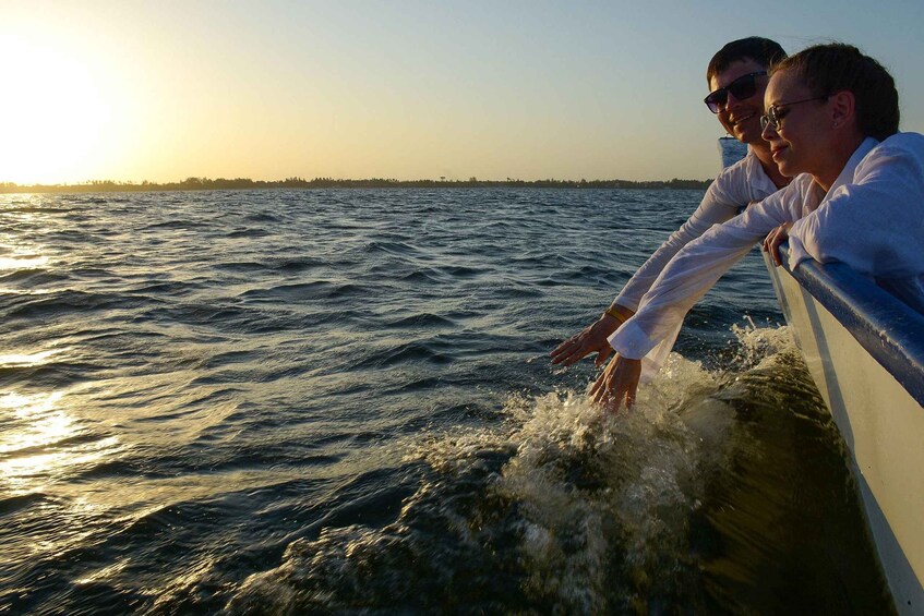 Two people leaning over a boat's edge, looking at the water. 2