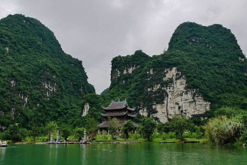 A traditional building by a calm lake surrounded by lush green mountains. 5