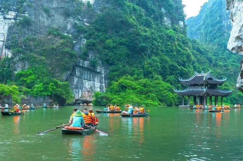 A river with boats, a traditional pavilion, and lush greenery. 3