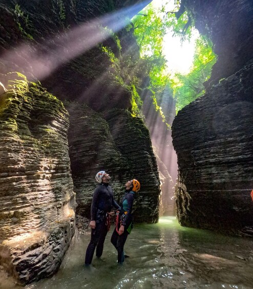 Two people in a cave with water and sunlight filtering through. 2