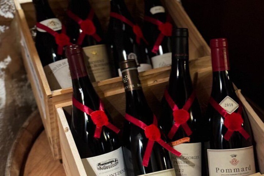 A wooden crate with several bottles of wine, each tied with a red ribbon. 5