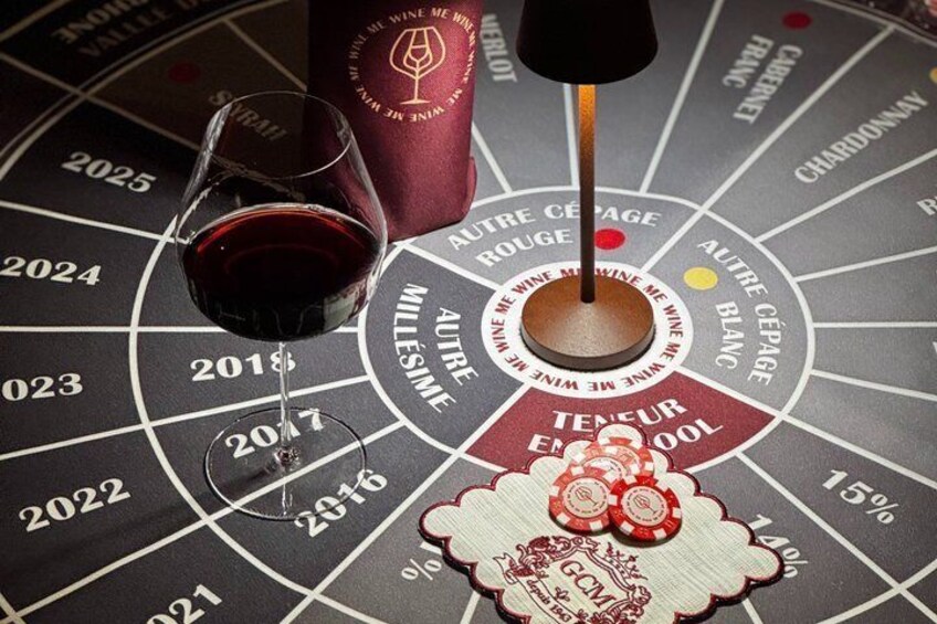 A roulette wheel with a glass of red wine and a bottle of wine. 1