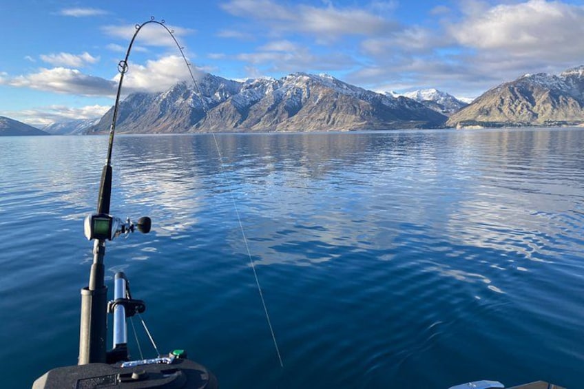 A fishing rod in a calm lake with mountains in the background. 3