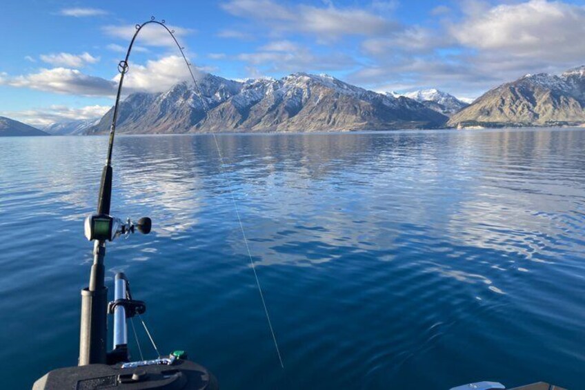 A fishing rod in the water with mountains in the background. 3