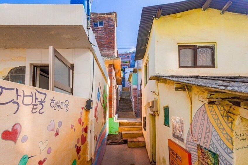 A narrow alley with colorful graffiti and a staircase leading to a building. 4