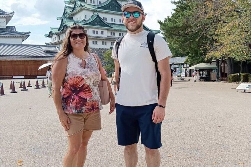 Two people standing in front of a traditional Japanese building with a green roof. 1