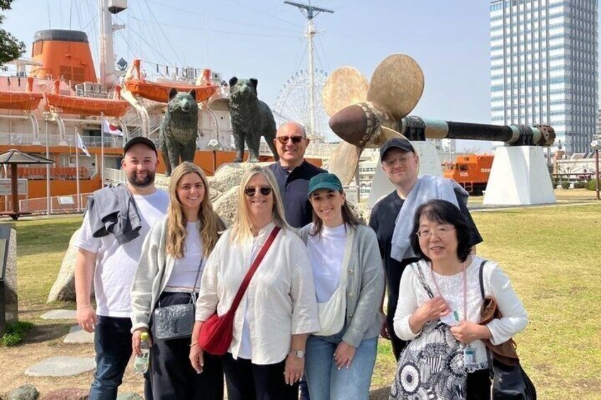 A group of people standing in front of a large cannon and a bear statue. 5