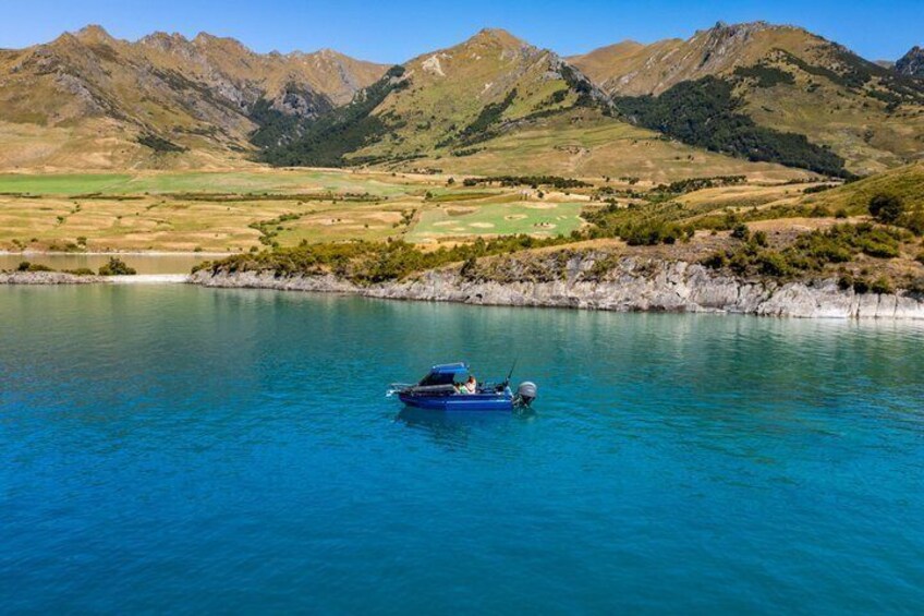 A boat on a clear blue lake surrounded by mountains. 4