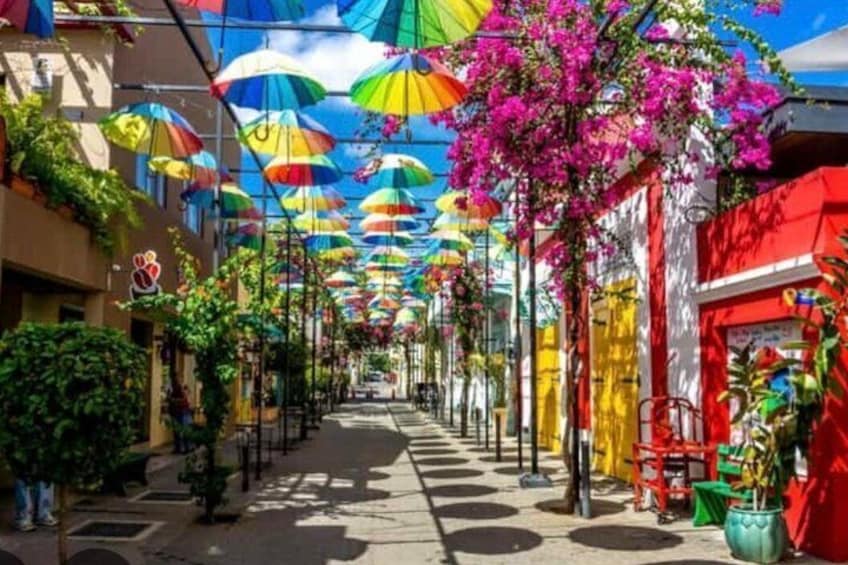 A colorful street with vibrant umbrellas and bougainvillea flowers. 2