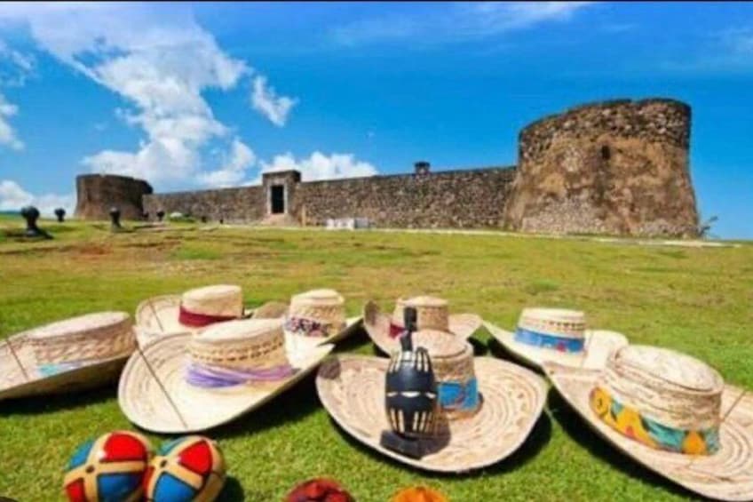 A historical fort with a large stone wall and a smaller building, surrounded by green grass. 3