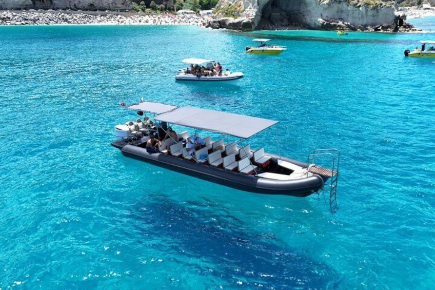 A boat with a canopy and several passengers on a turquoise sea. 1