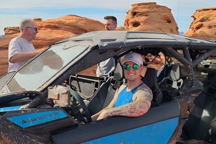 A person in a blue off-road vehicle with a desert landscape in the background. 1