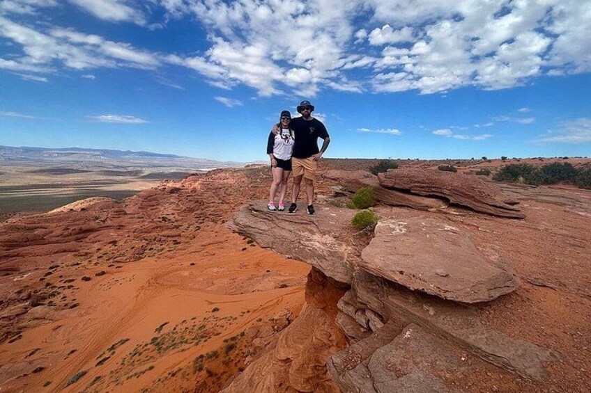 Two people standing on a rocky outcrop with a vast landscape in the background. 4