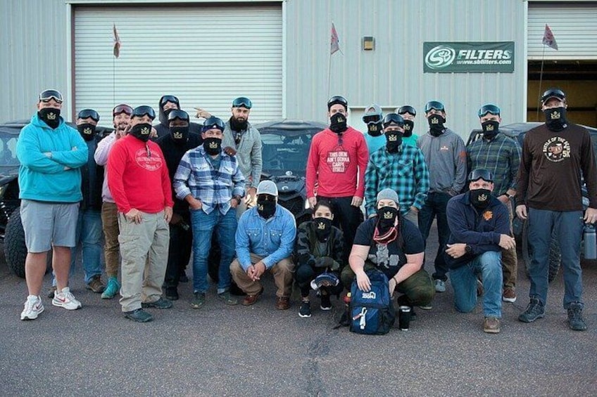 A group of people in casual attire posing in front of a building with a sign that reads 'FILTERS'. 2