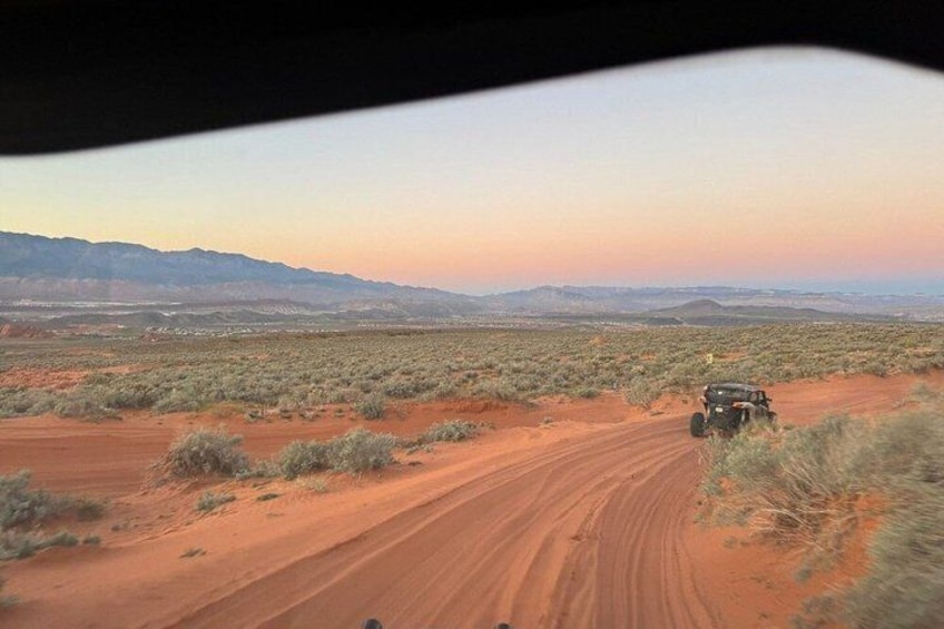 A desert landscape with a dirt road and a vehicle. 2