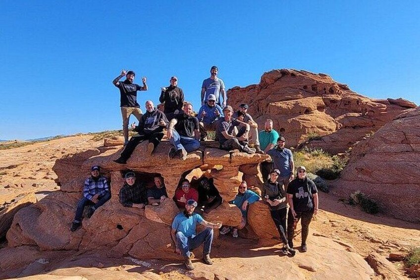 A group of people posing on a rocky outcrop with a clear blue sky in the background. 4