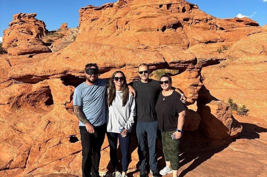 A group of people standing in front of a large red rock formation. 2